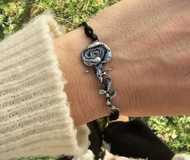 Bransoletka z różą w odcieniu ciemnego srebra, na czarnym sznurku