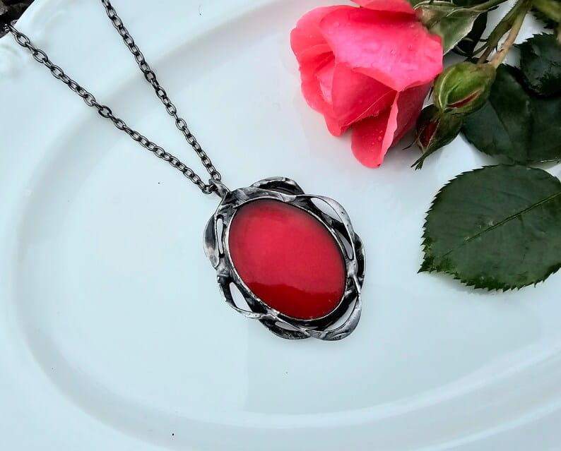 Ornamentalny wisior z owalnym . szklanym  oczkiem w czerwonym kolorze (oprawa w kolorze ciemnego srebra)